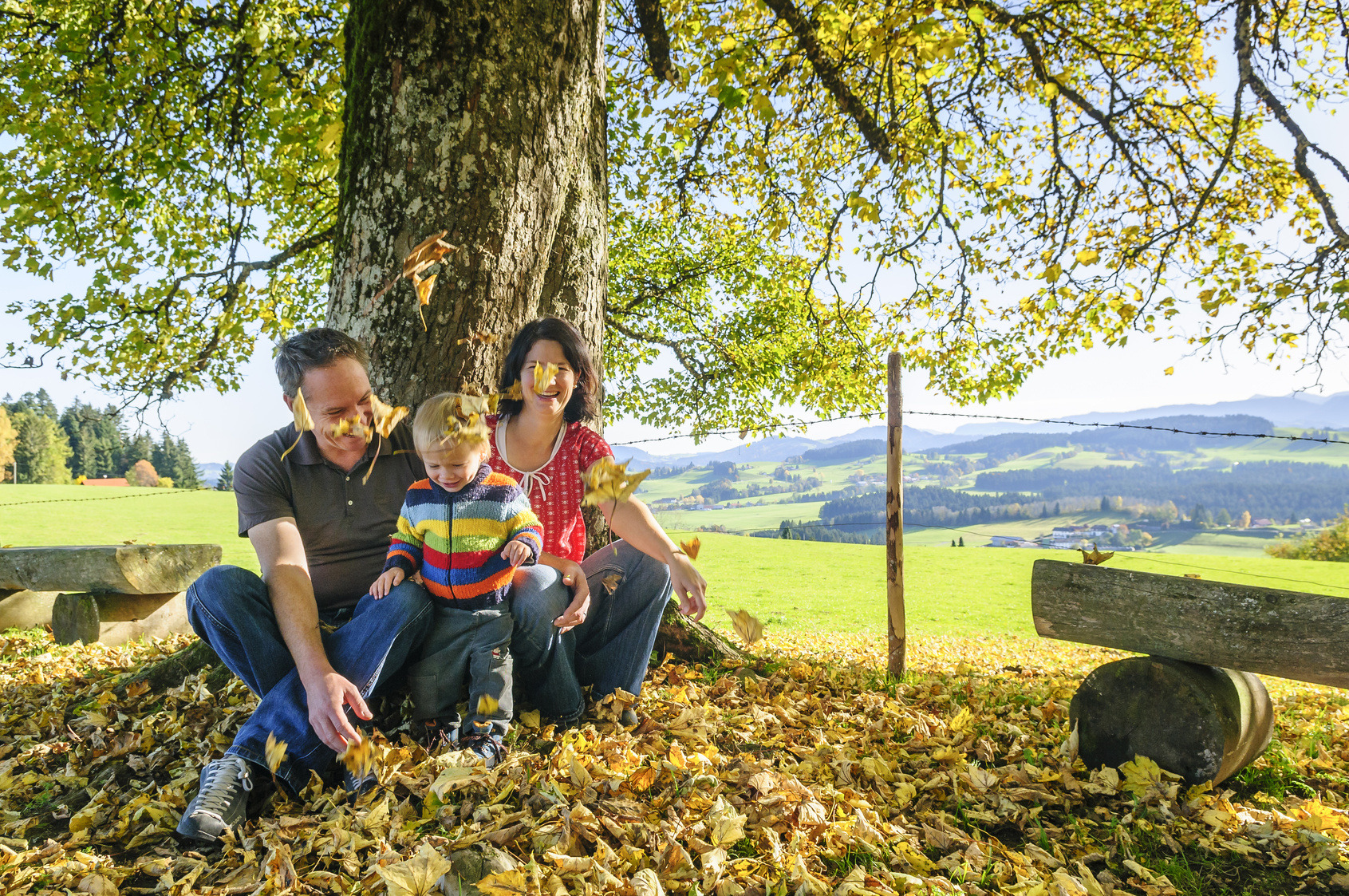 Familie unter einem Ahornbaum im Herbst mit Blick übers Voralpenland